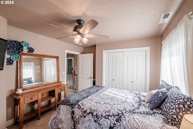 carpeted bedroom featuring a closet, a textured ceiling, and ceiling fan