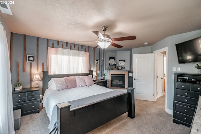 carpeted bedroom featuring ceiling fan and a textured ceiling