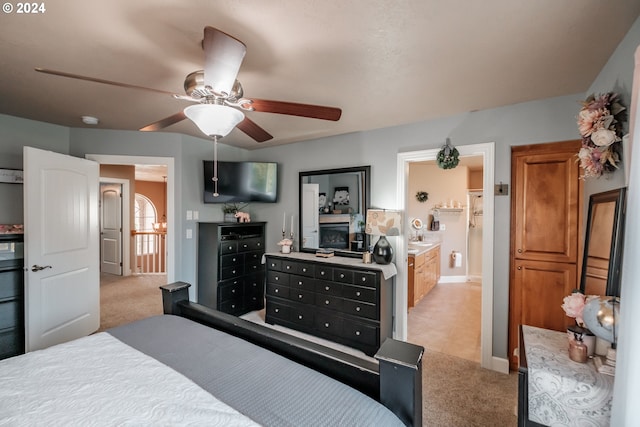 bedroom with light carpet, ceiling fan, and connected bathroom