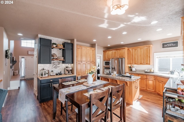 kitchen with appliances with stainless steel finishes, light wood-style floors, a kitchen island, a sink, and recessed lighting