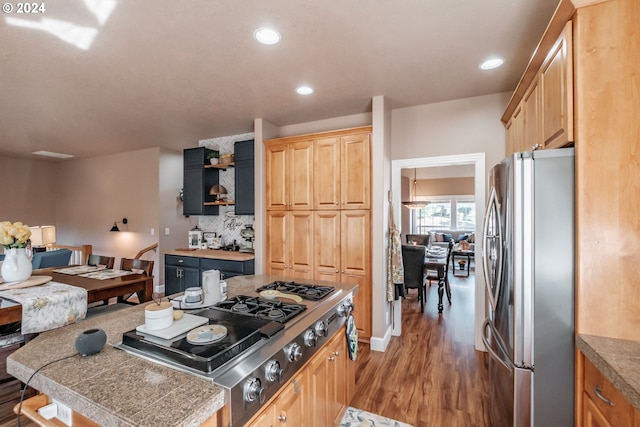 kitchen with stainless steel appliances, wood-type flooring, light brown cabinets, and decorative backsplash