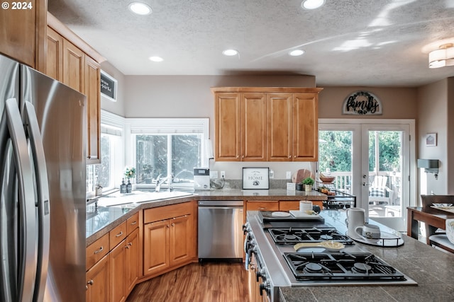 kitchen with french doors, stainless steel appliances, a textured ceiling, and light hardwood / wood-style flooring