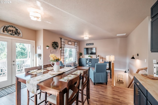 dining space with french doors, wood-type flooring, and a textured ceiling