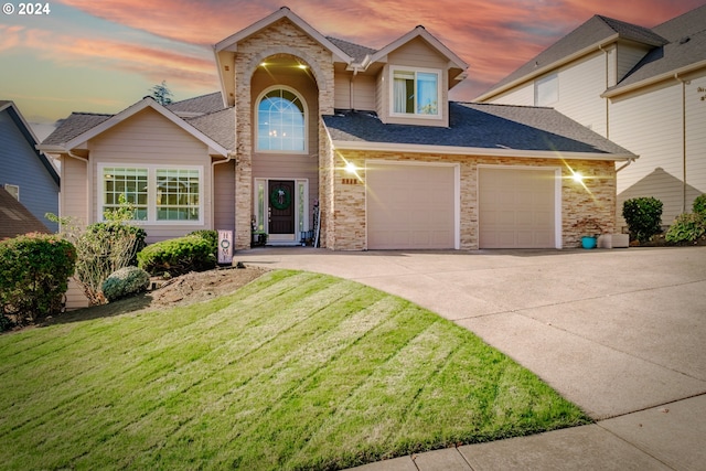 traditional-style house featuring concrete driveway, a yard, roof with shingles, an attached garage, and stone siding