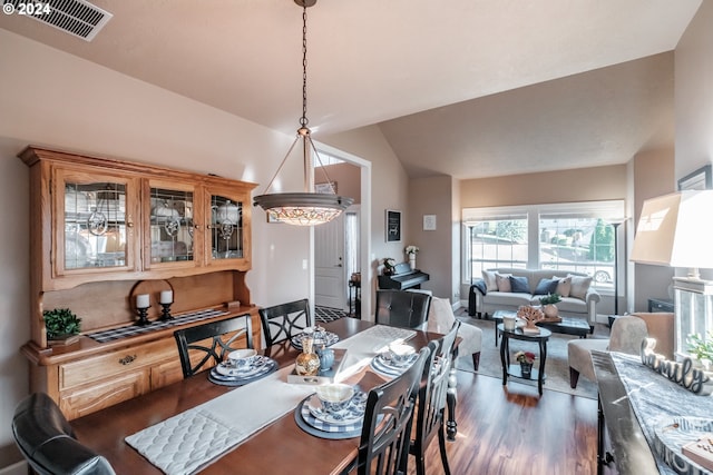 dining room with dark hardwood / wood-style flooring, lofted ceiling, and a notable chandelier