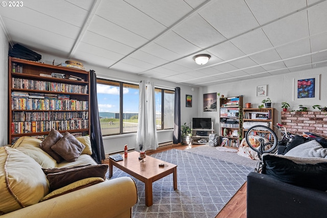 living room with a baseboard heating unit, a drop ceiling, and wood-type flooring