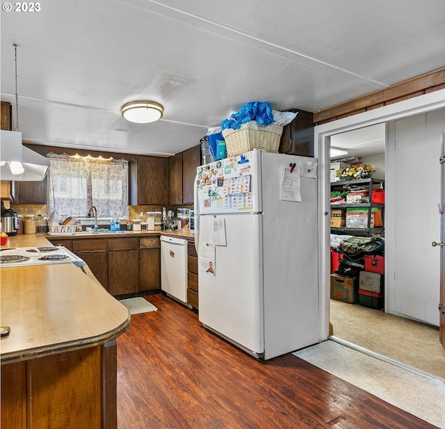 kitchen with white appliances, dark brown cabinetry, range hood, dark hardwood / wood-style flooring, and backsplash