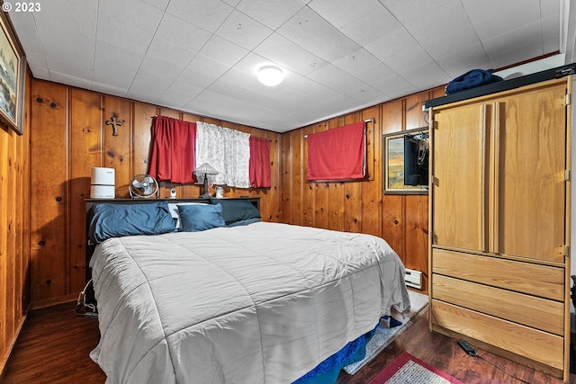 bedroom with wooden walls and dark hardwood / wood-style flooring