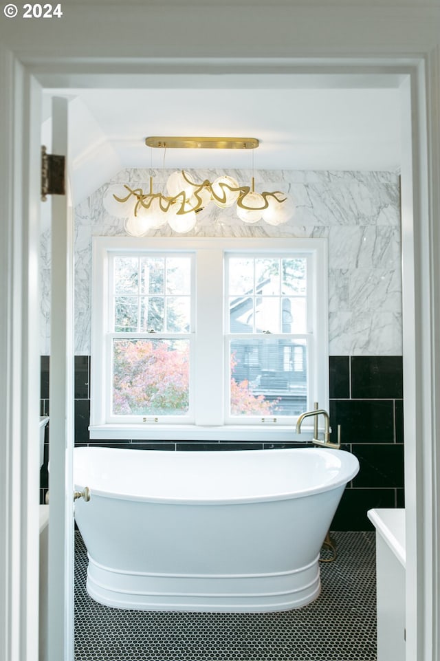 bathroom featuring tile patterned floors, a tub to relax in, and tile walls