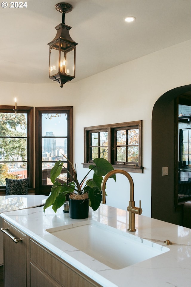 interior details featuring pendant lighting, light stone counters, and sink