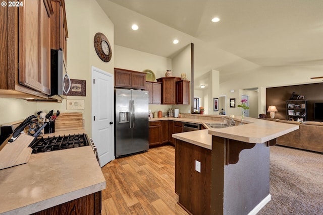 kitchen featuring sink, stainless steel appliances, kitchen peninsula, lofted ceiling, and a breakfast bar