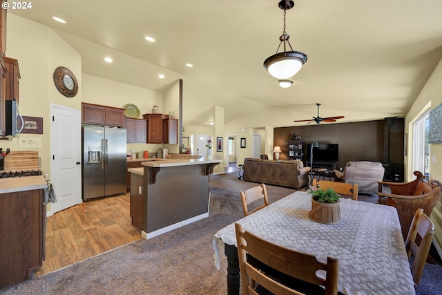 carpeted dining area with ceiling fan and vaulted ceiling