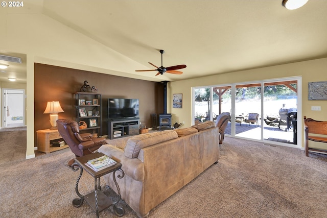 living room with carpet flooring, ceiling fan, a wood stove, and vaulted ceiling