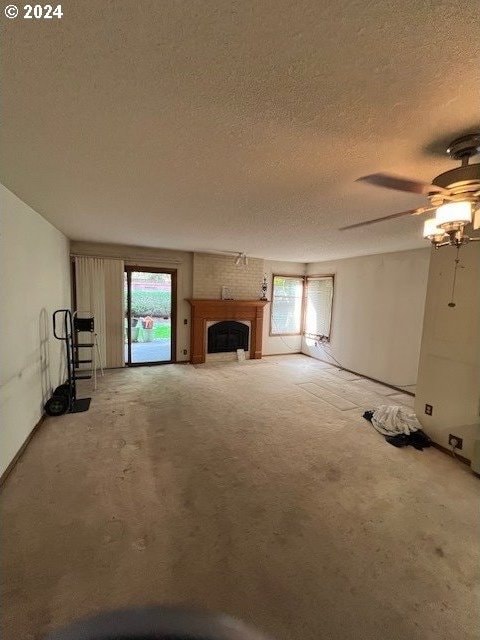 unfurnished living room with a textured ceiling, ceiling fan, and a wealth of natural light