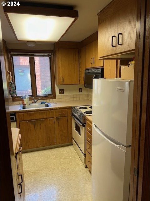 kitchen featuring sink, range, decorative backsplash, and white refrigerator