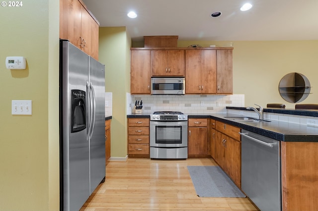 kitchen with backsplash, sink, stainless steel appliances, and light hardwood / wood-style floors