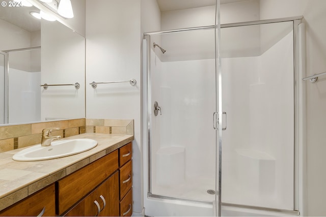 bathroom featuring decorative backsplash, vanity, and a shower with shower door