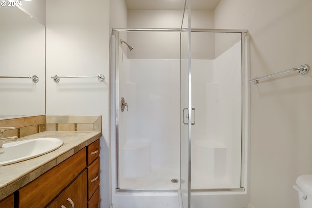 bathroom featuring a shower with door, vanity, and toilet