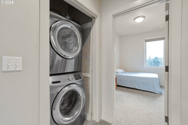 laundry area with light colored carpet and stacked washing maching and dryer