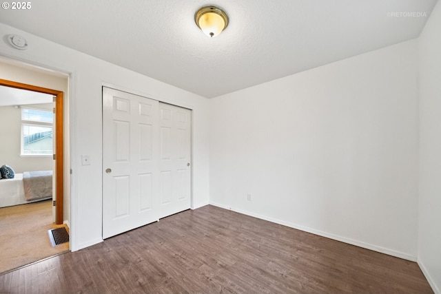 unfurnished bedroom featuring hardwood / wood-style flooring, a closet, and a textured ceiling