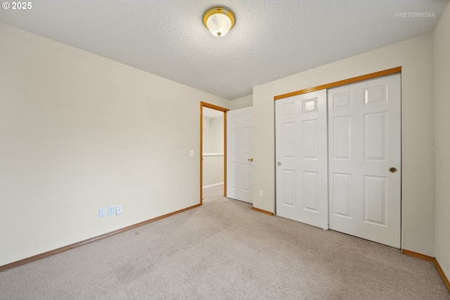 unfurnished bedroom featuring light colored carpet, a closet, and a textured ceiling