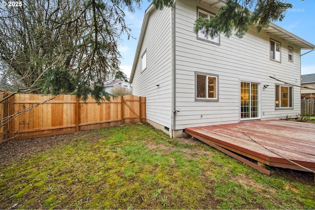 rear view of property featuring a wooden deck and a lawn