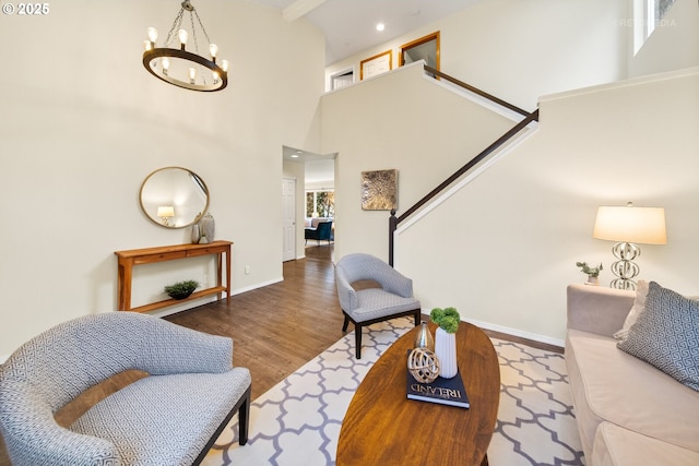 living room with a towering ceiling, wood-type flooring, and a notable chandelier