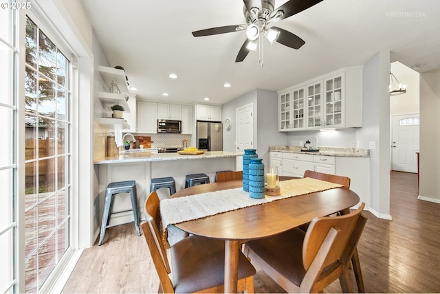 dining area with sink, ceiling fan, and light wood-type flooring