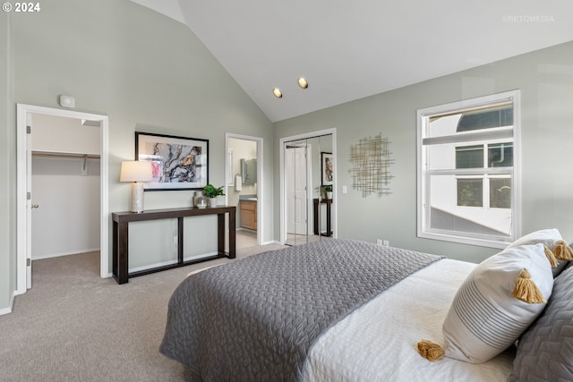 carpeted bedroom with a spacious closet, connected bathroom, and high vaulted ceiling