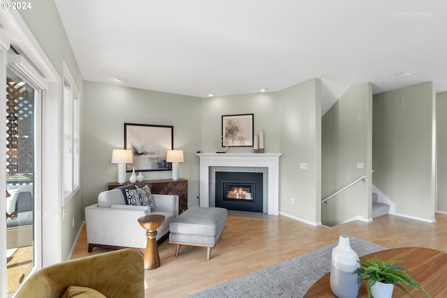 living room featuring a wealth of natural light, light hardwood / wood-style flooring, and a tile fireplace