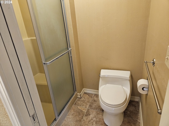 bathroom featuring a shower with door and toilet