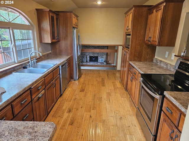 kitchen featuring light hardwood / wood-style floors, vaulted ceiling, stainless steel appliances, and sink