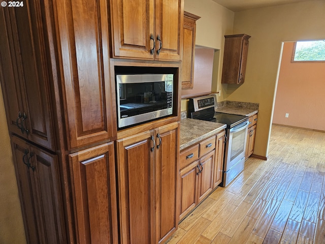 kitchen featuring light hardwood / wood-style floors, appliances with stainless steel finishes, and dark stone counters