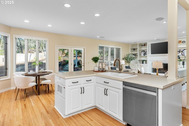 kitchen with dishwasher, white cabinets, sink, built in shelves, and light wood-type flooring