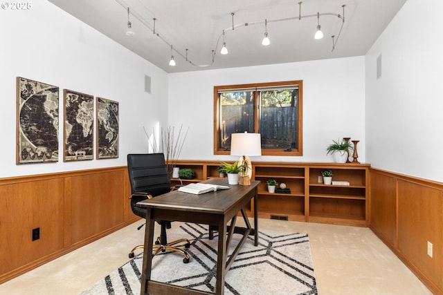 home office featuring rail lighting, light colored carpet, and wood walls