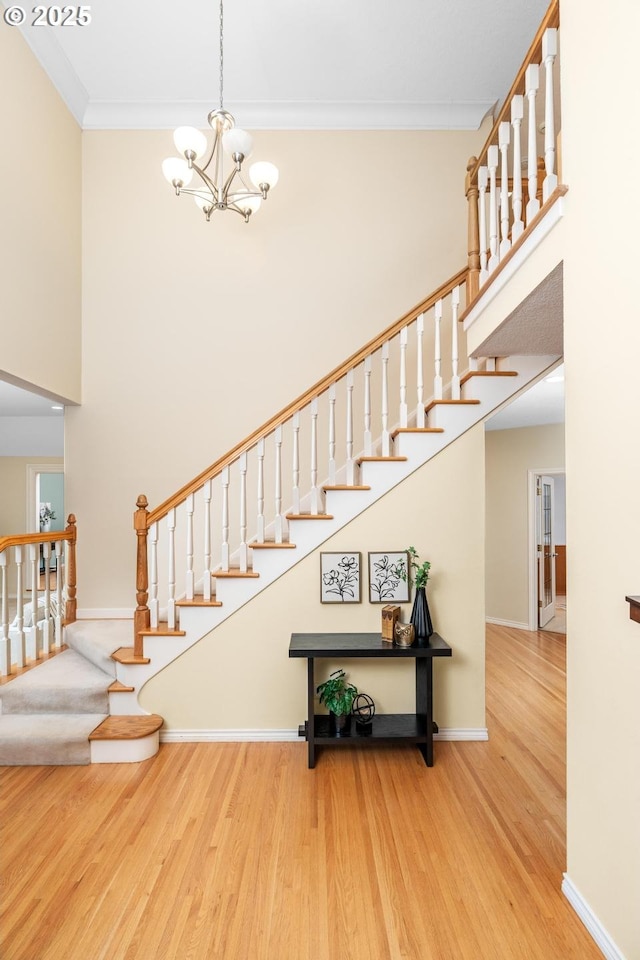 staircase with ornamental molding, a notable chandelier, and hardwood / wood-style floors