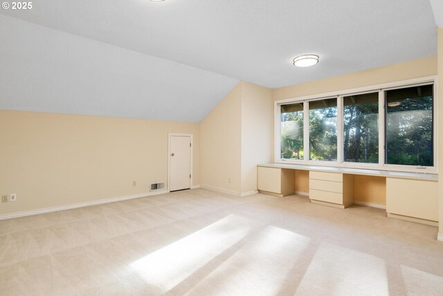 bonus room featuring light carpet, built in desk, and lofted ceiling