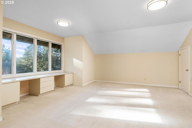 bonus room featuring light colored carpet, built in desk, and lofted ceiling