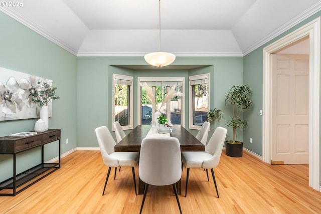 dining space with crown molding, light hardwood / wood-style floors, and vaulted ceiling