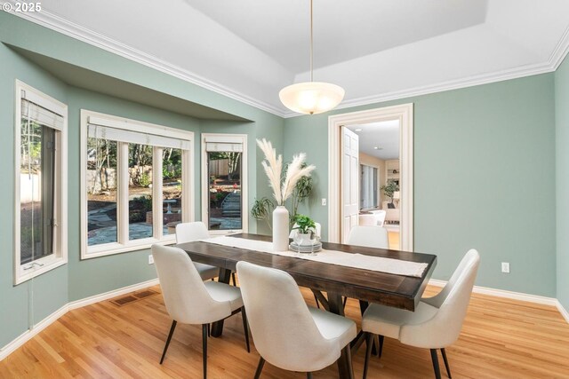 dining room with light hardwood / wood-style floors and crown molding