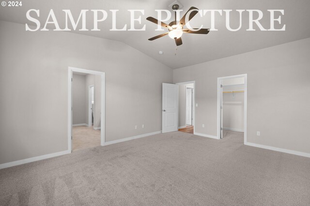 unfurnished bedroom with a closet, ceiling fan, a walk in closet, carpet flooring, and vaulted ceiling