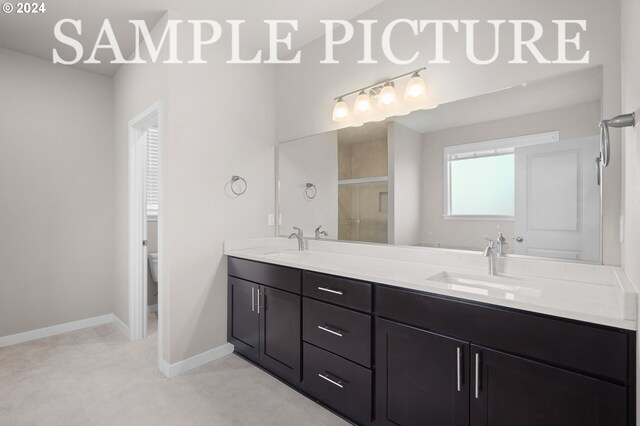 bathroom with toilet and dual bowl vanity