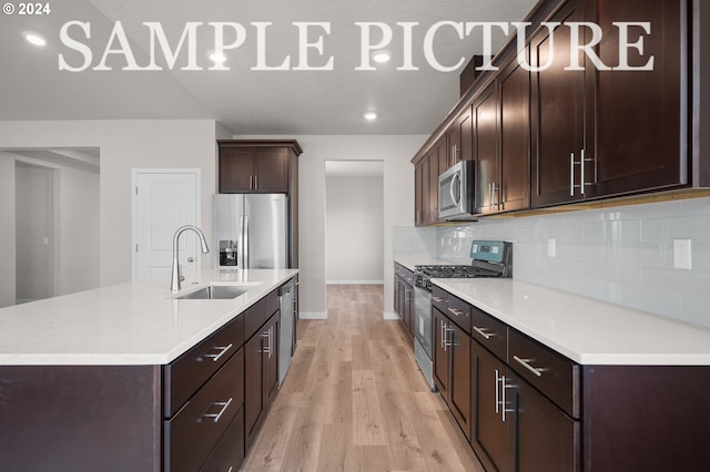 kitchen with sink, light hardwood / wood-style floors, dark brown cabinets, stainless steel appliances, and a kitchen island with sink