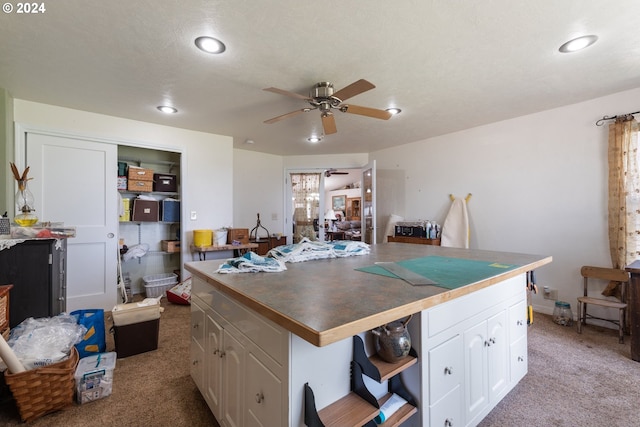 kitchen with light carpet, ceiling fan, and white cabinets