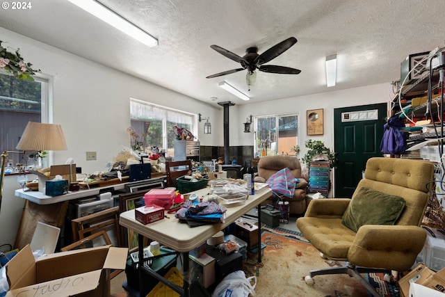 office area featuring ceiling fan, a textured ceiling, and a wood stove