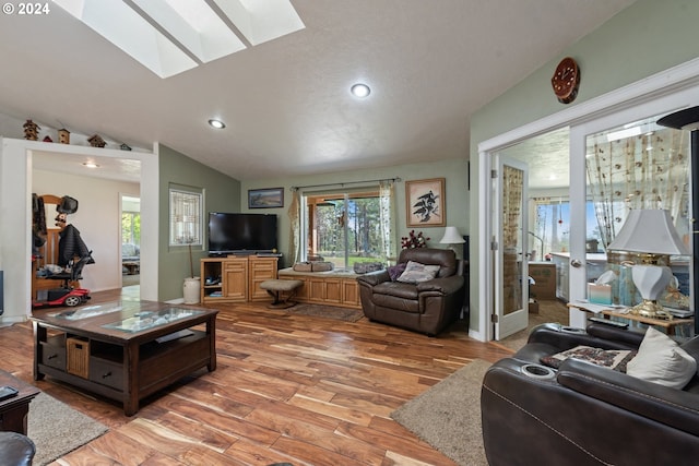 living room with hardwood / wood-style flooring and lofted ceiling with skylight