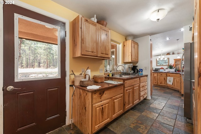 kitchen with lofted ceiling, sink, hanging light fixtures, and light brown cabinets