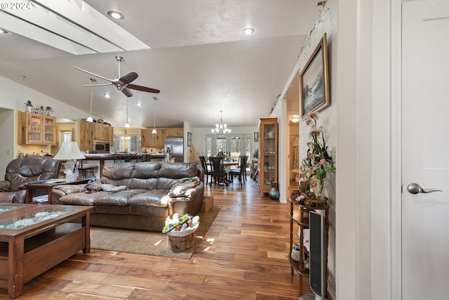 living room featuring lofted ceiling, ceiling fan with notable chandelier, and light wood-type flooring