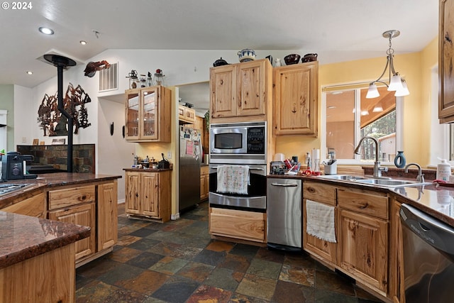 kitchen with sink, decorative light fixtures, vaulted ceiling, and appliances with stainless steel finishes