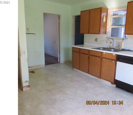 kitchen featuring backsplash, white dishwasher, and sink